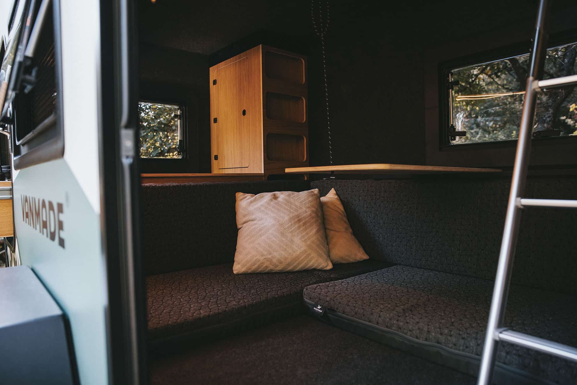 Kuckoo Camper Gemeinsam Draussen Sitzecke mit Kissen und Tisch und Wandschrank