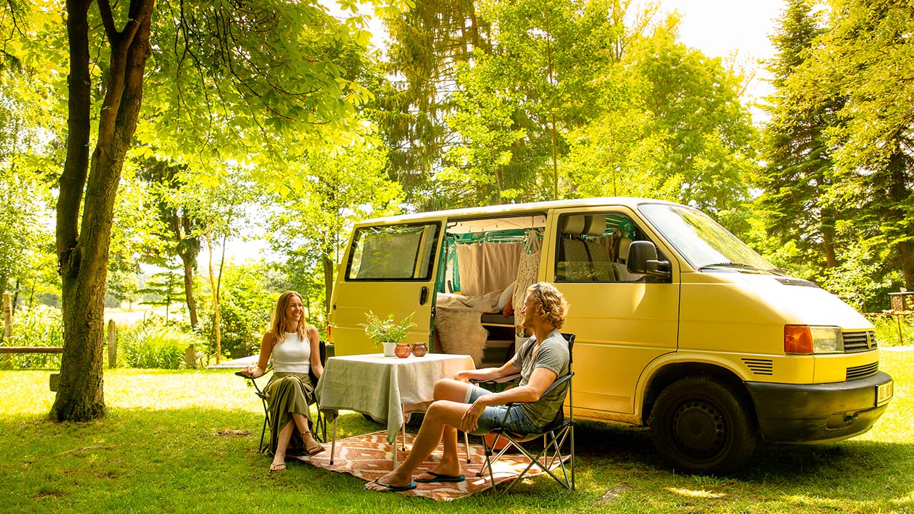 VW Bus auf einer Wiese mit Pärchen beim Campen VanSite