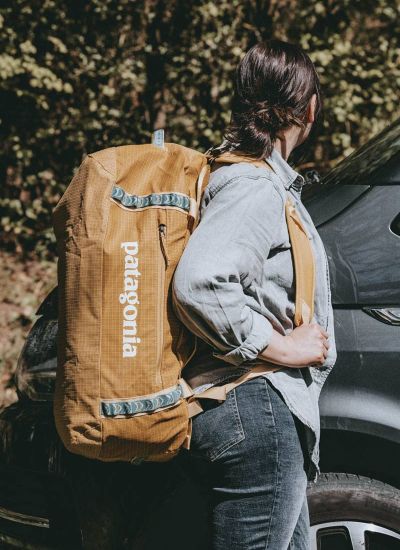 Frau mit gelber Patagonia Black Hole Duffel 55 als Rucksack