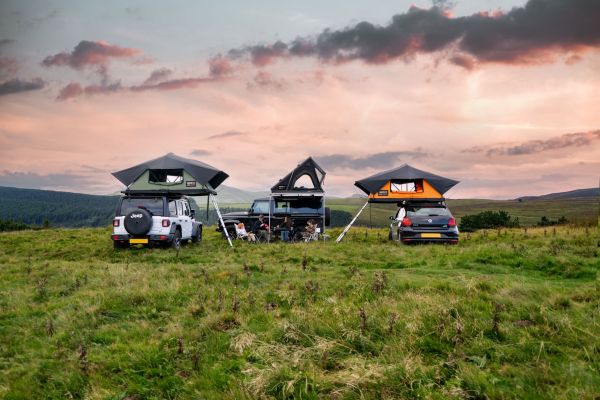 Tentbox Dachzelte Camüing Szene auf einer Wiese mit drei Fahrzeugen